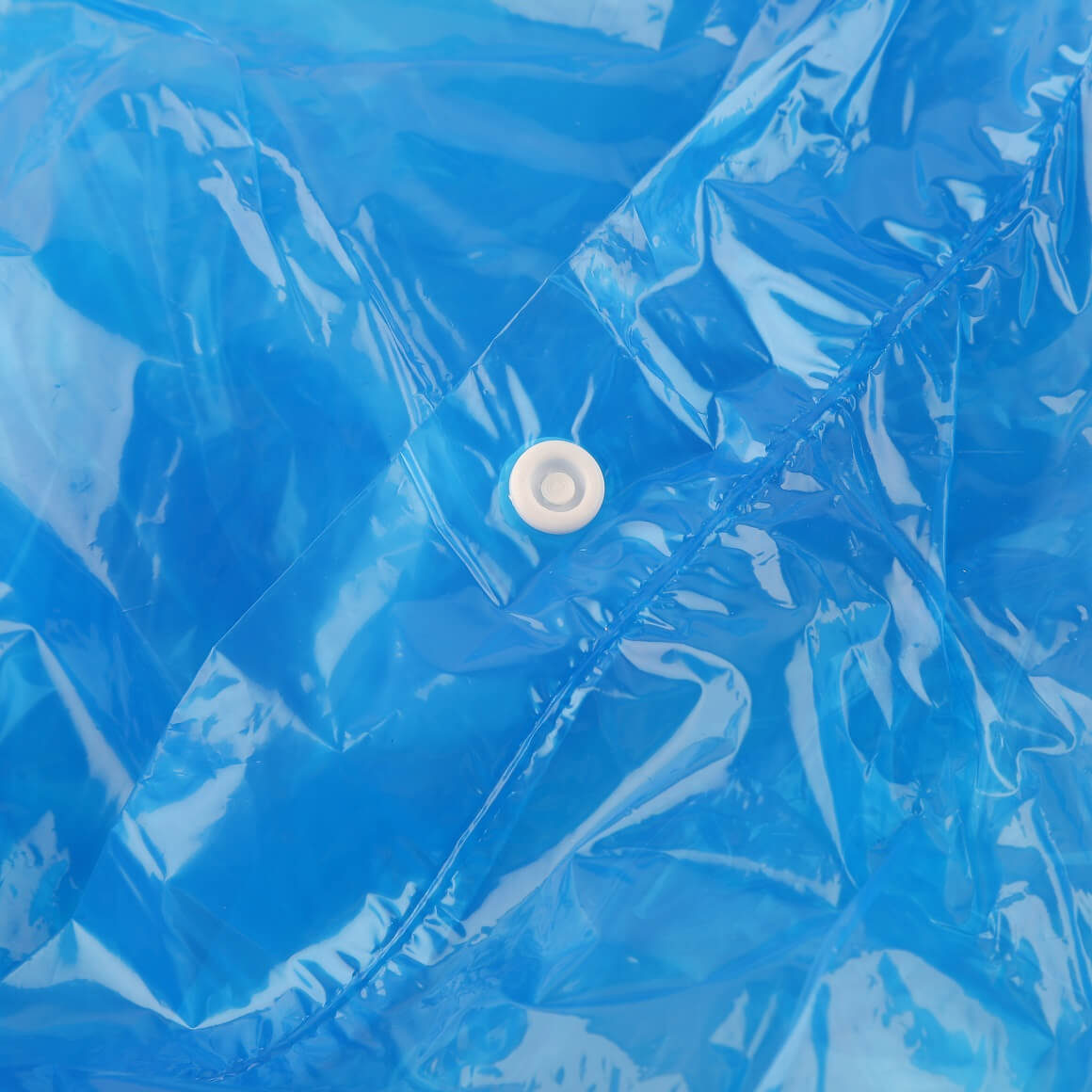 Close-up of unfolded blue rain poncho showing snap button and waterproof texture.